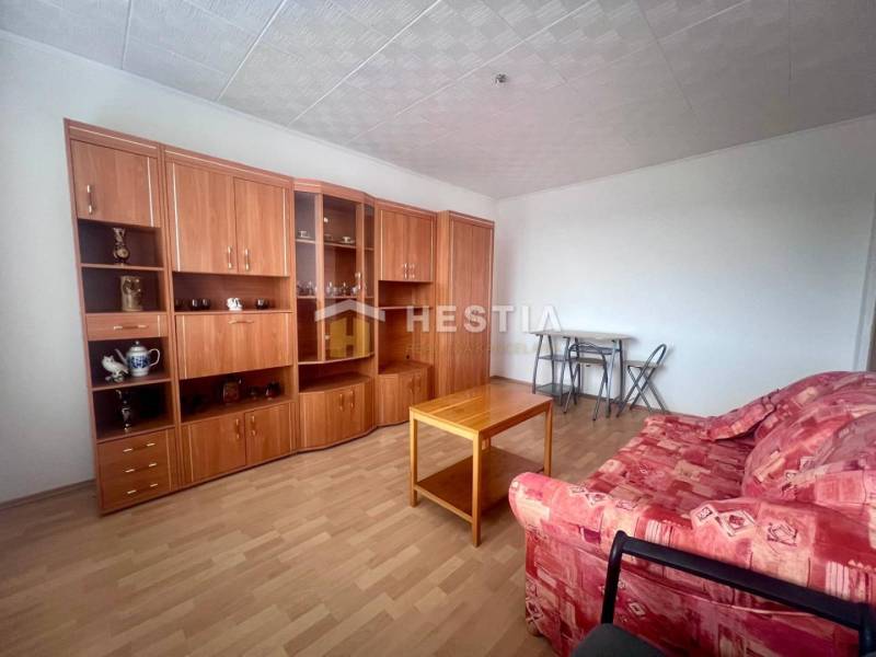 A living room in a three-room apartment with a red sofa and a wooden wall unit.