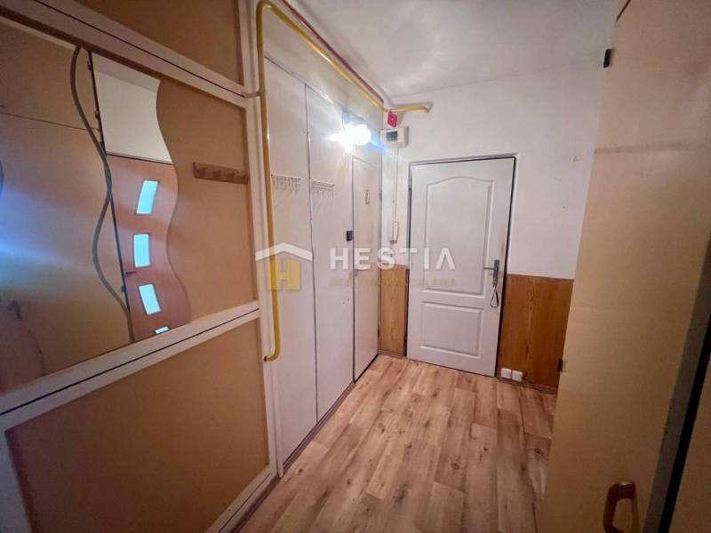 A hallway in a 3-room apartment with a wooden floor, a mirror, and a built-in wardrobe.