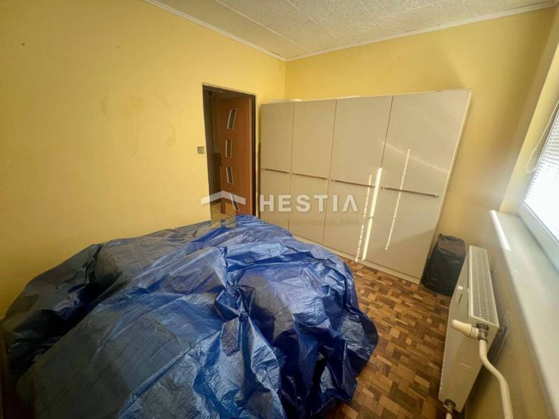 A room with a wardrobe, radiator, and covered furniture in a 3-room apartment.