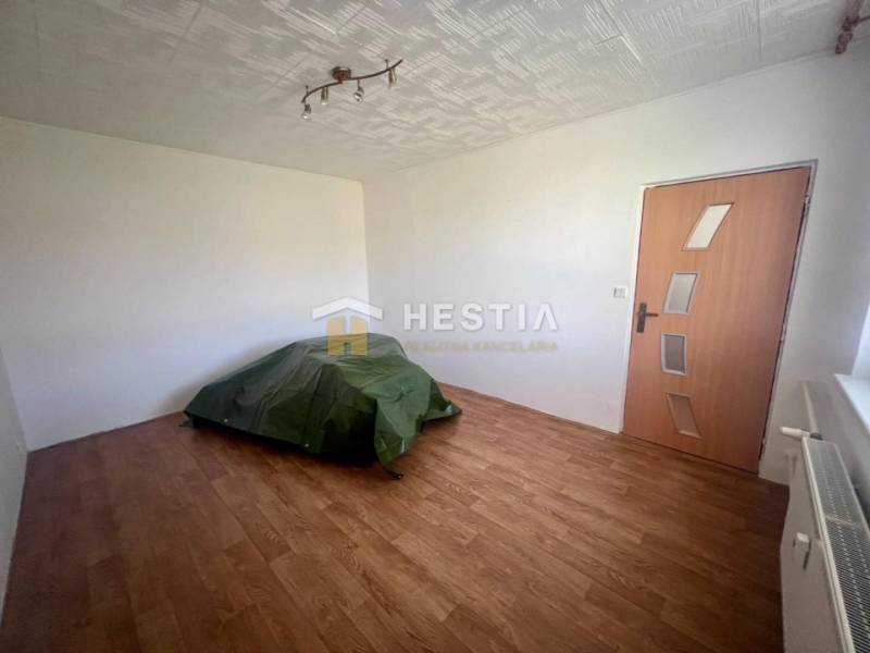 A room in a 3-room apartment with a floor, radiator, door, and simple lighting.