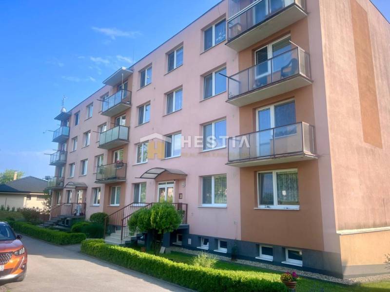 A four-story apartment building in Moravské Lieskové with balconies and parking in front of the building.