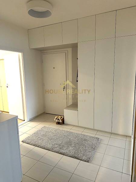 The entrance hall of a 3-room apartment with white cabinets and tiles, carpet on the floor.