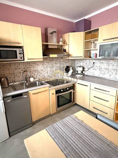 A kitchen in a 3-room apartment with wooden decor cabinets, a dryer, and an oven.