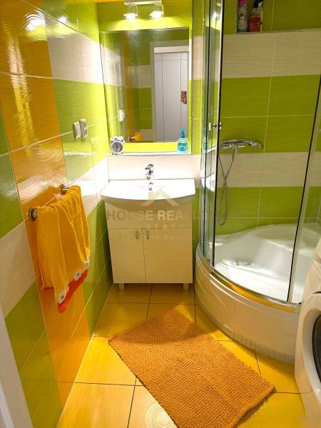 A colorful bathroom in a 3-room apartment with a modern shower cabin and bright tiles.