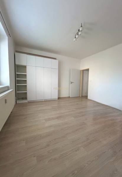 A bright room with a white wardrobe and a wooden decor floor in a studio apartment.