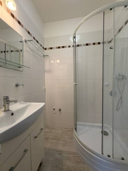 Bathroom with white tiles and a shower in a studio apartment.