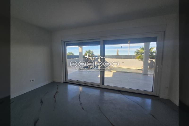 Interior of a villa with large glazing and a view of the exterior with a pool.