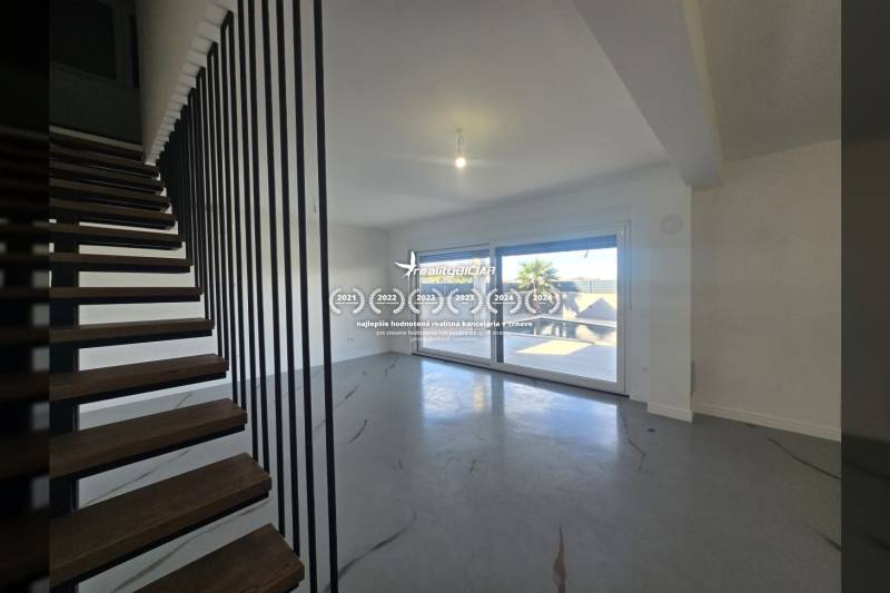 Living room in a villa with modern stairs and large windows.