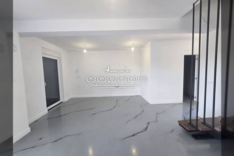 A spacious room in a villa with white walls and a gray floor with a decor.