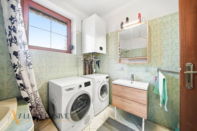 Bathroom with a washing machine, sink, and gas boiler in a family house.