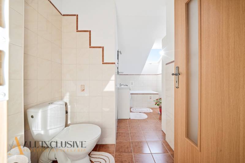 Bathroom with toilet, sink, and bathtub in a family house, floor with ceramic tiles.