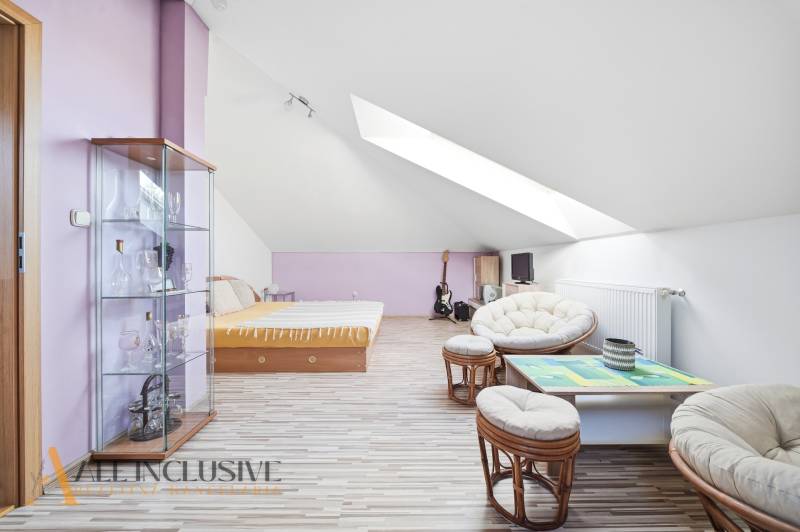 Attic room in a family house with a wooden decor floor, furniture, and skylights.
