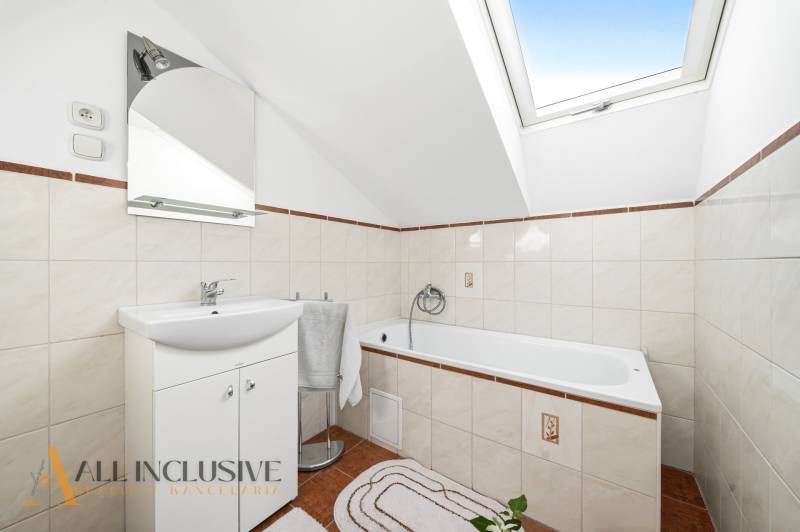 Bathroom with a skylight, white sanitary ware, and tiles in a family house.