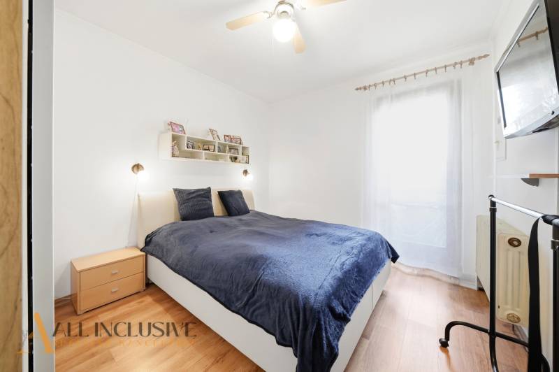 Bedroom in a family house with a bed, wooden floor decor, and a TV on the wall.