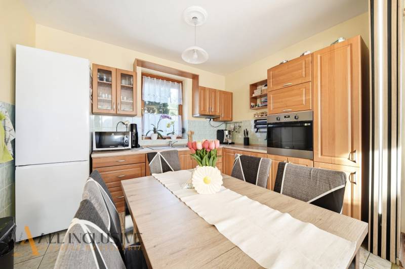 A kitchen in a family house with wooden decor furniture and equipment, floral decoration on the table.