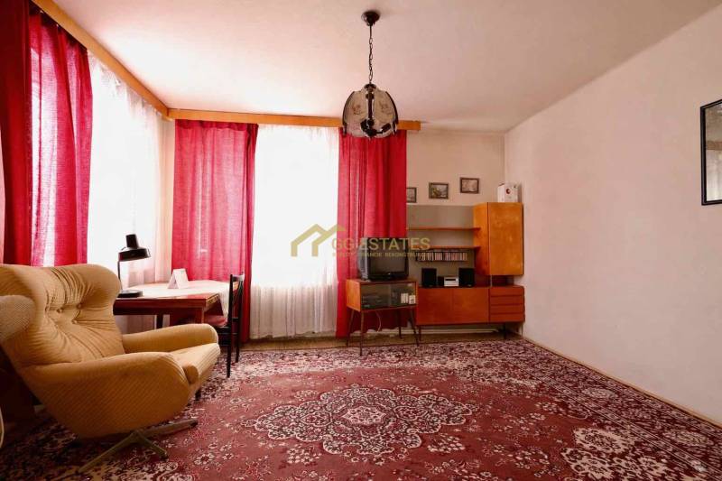 Living room in a family house with a red carpet, an armchair, and curtains on the windows.