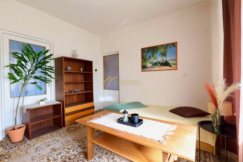 Living room in a family house with carpeted floor, wooden furniture, and a picture of a beach.