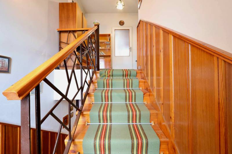 A staircase with carpet and wooden panels in a family house, with a door at the end of the hallway.