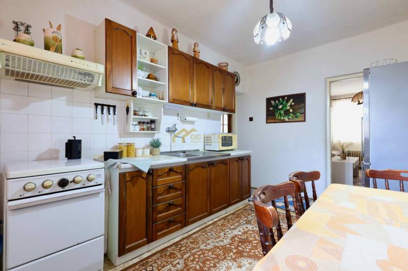 A kitchen in a family house with wooden cabinets, a dining table, and kitchen appliances.