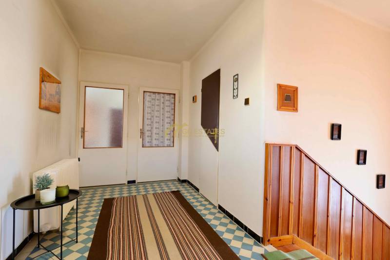 A family house with patterned tiles, wooden stairs, and simple wall decorations.