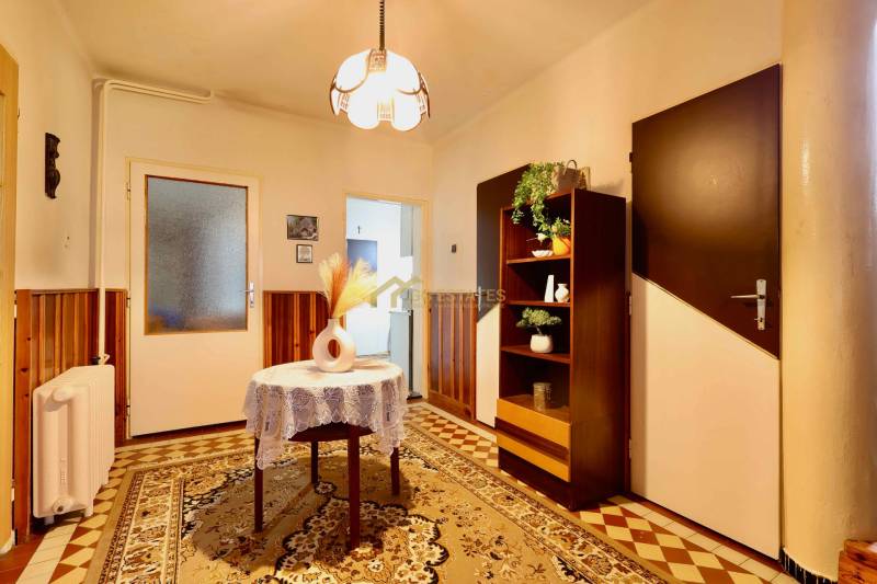 Interior of a family house with carpet flooring, a cabinet and lighting in the background.