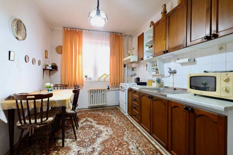 Traditional kitchen in a family house with wooden cabinets and orange curtains.