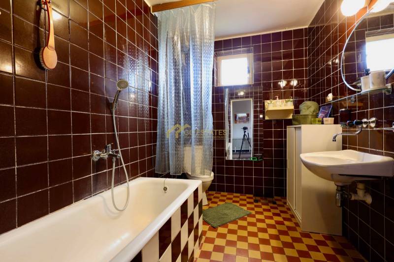 A bathroom in a family house with stylish dark brown tiles and a classic bathtub.