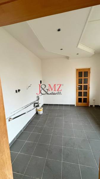 An empty room in a two-room apartment, dark tiled floor, white walls, wooden doors.