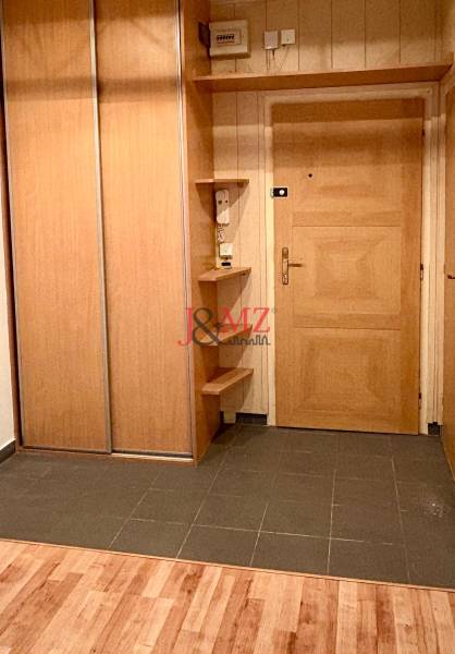 The entrance hall of a two-room apartment with a wooden decor floor and a spacious wardrobe.