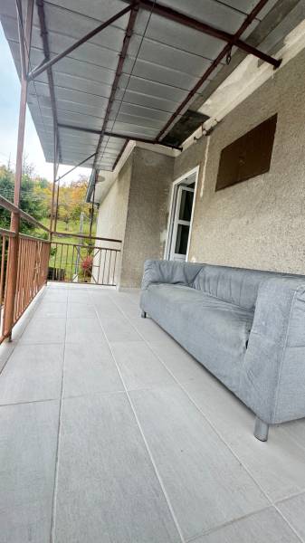 The terrace of a family house in Pruské with a sofa and a view of greenery.
