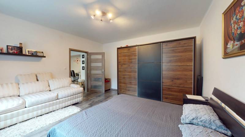 A bedroom in a family house with a wood-decor floor, a large wardrobe, and a comfortable sofa.