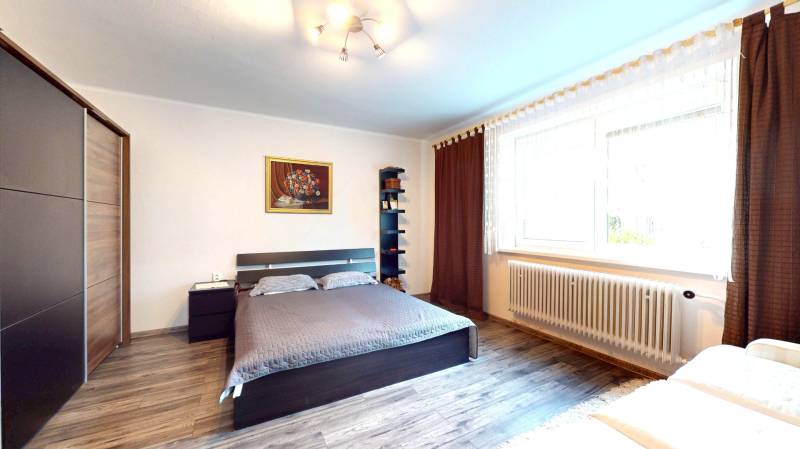 Bedroom in a family house with a bed, cabinet, painting, and floor with a wooden decor.