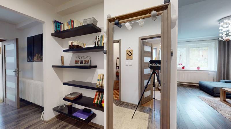 Interior of a family house with an open passage, bookshelf, and wooden floor decor.