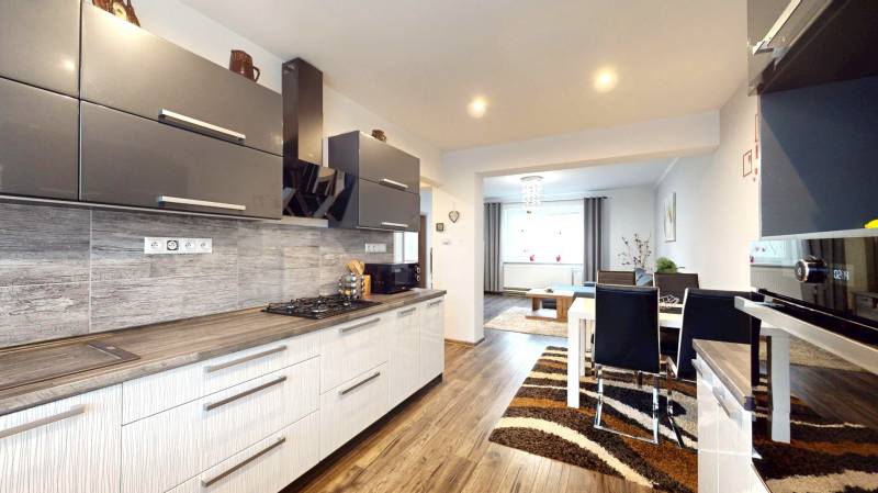 A kitchen in a family house with a wooden decor floor and a dining table.