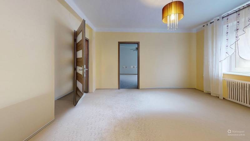 A bright room in a family house with curtains, a chandelier, and open doors.
