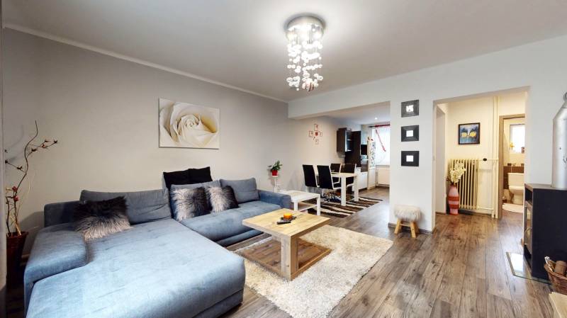 Living room with wood-patterned flooring, gray sofa, and dining table in a family house.