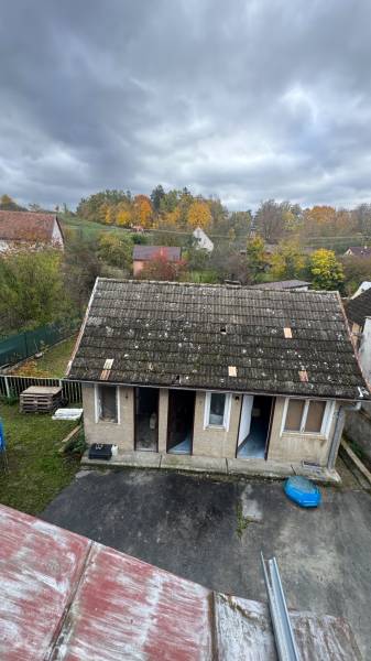 A family house in Pruské with a worn-out roof, a yard, and autumn nature in the background.