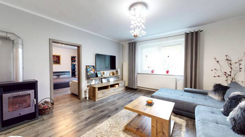 Living room in a family house with a fireplace, wooden decor flooring, and a sofa set.