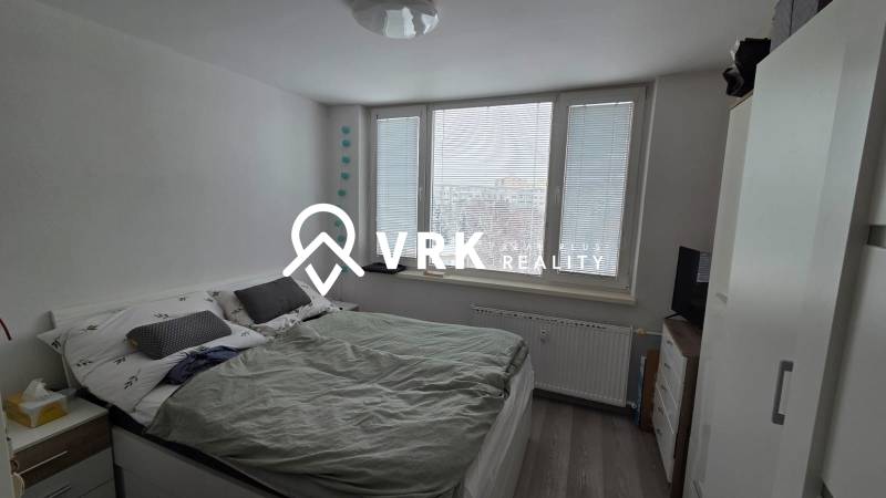 Bedroom with a double bed, large windows, and a wood-patterned floor in a 3-room apartment.