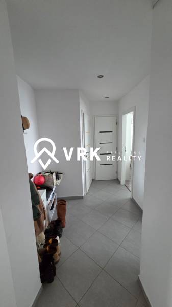 Hallway in a 3-room apartment with gray tiles, a shoe cabinet, and shoes on the floor.