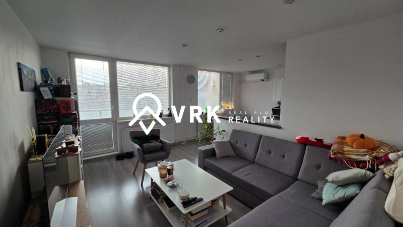 Living room of a 3-room apartment with a sofa, coffee table, and wooden decor flooring.