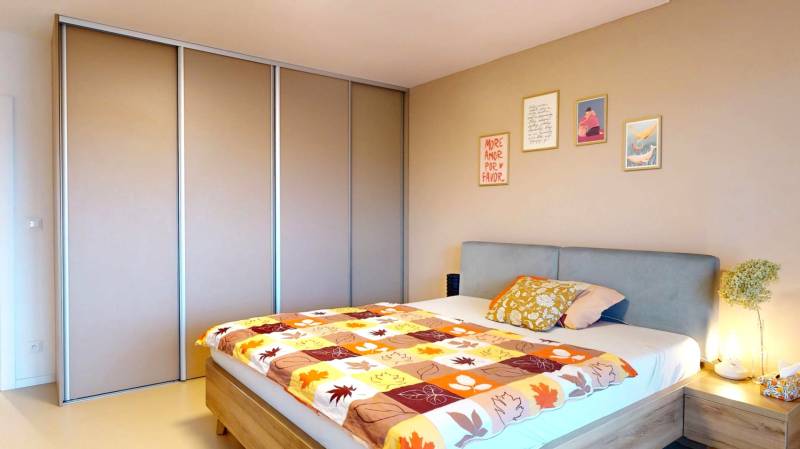 Bedroom in a family house with a bed, built-in wardrobe, and decorative paintings on the wall.