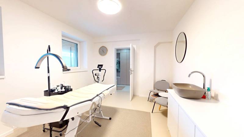 Interior of a family house with a massage table, sink, mirror, and chairs.