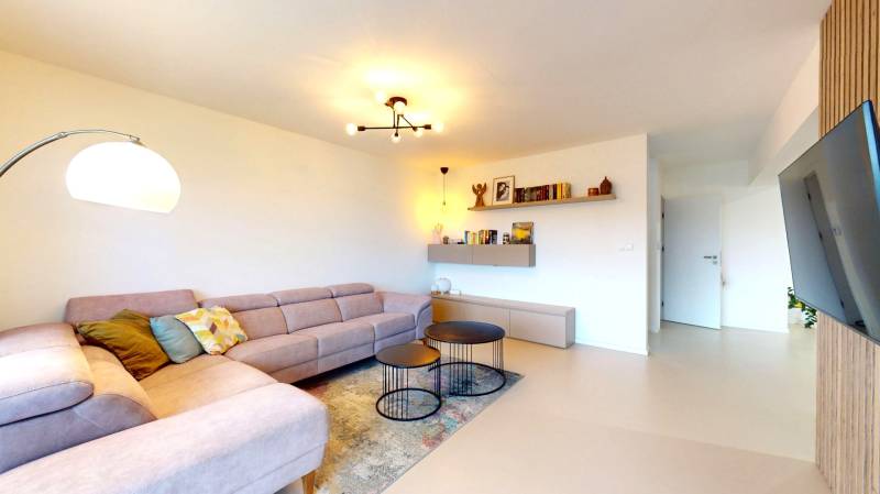 Living room in a family house with a corner sofa, round tables, and a wooden decor floor.