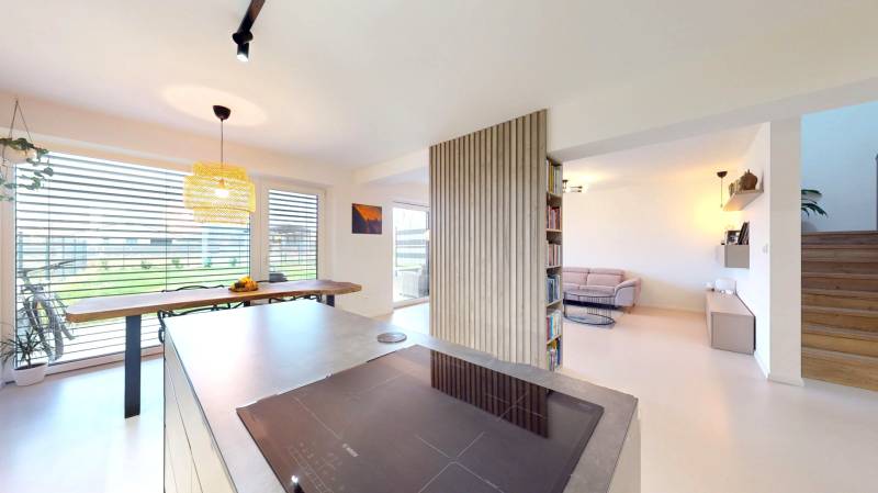 Open interior of a family house with a kitchen, dining area, and comfortable living corner.