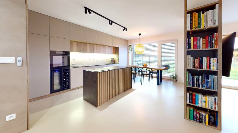 Open kitchen with dining table and bookshelf in a family house.