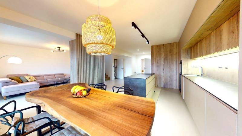 A kitchen in a family house with a wooden table, a sofa, and modern lighting.
