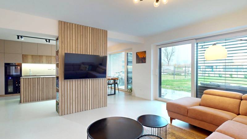 Living room with large windows, a comfortable sofa, and wooden decor on the wall.