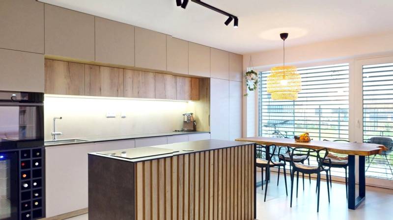 A kitchen in a family house with wooden decor furniture and large windows.