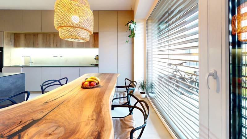 A kitchen in a family house with a solid wood table and a pendant light.